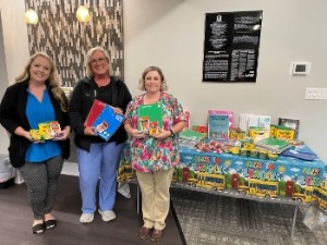 Bank employees and customer smiling with school supply donations