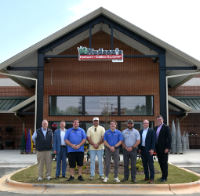 Men standing outside of local hardware store smiling at camera