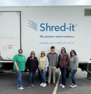 KS team members at a community shredding event smiling in front of shred truck