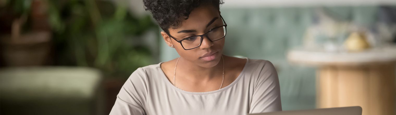 Woman staring at laptop screen intently.