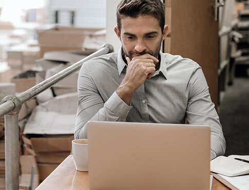 Man in deep thought sitting at laptop.