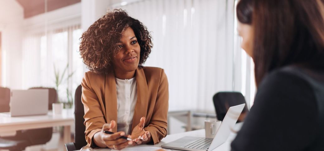 two businesswomen sitting across from each other at a desk