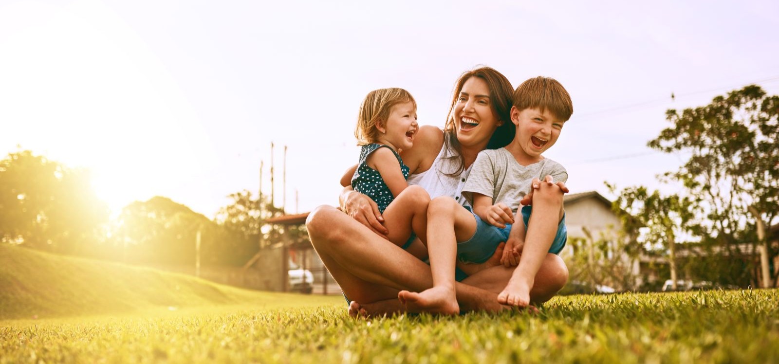 Mom, son, and daughter sitting outside in grass smiling