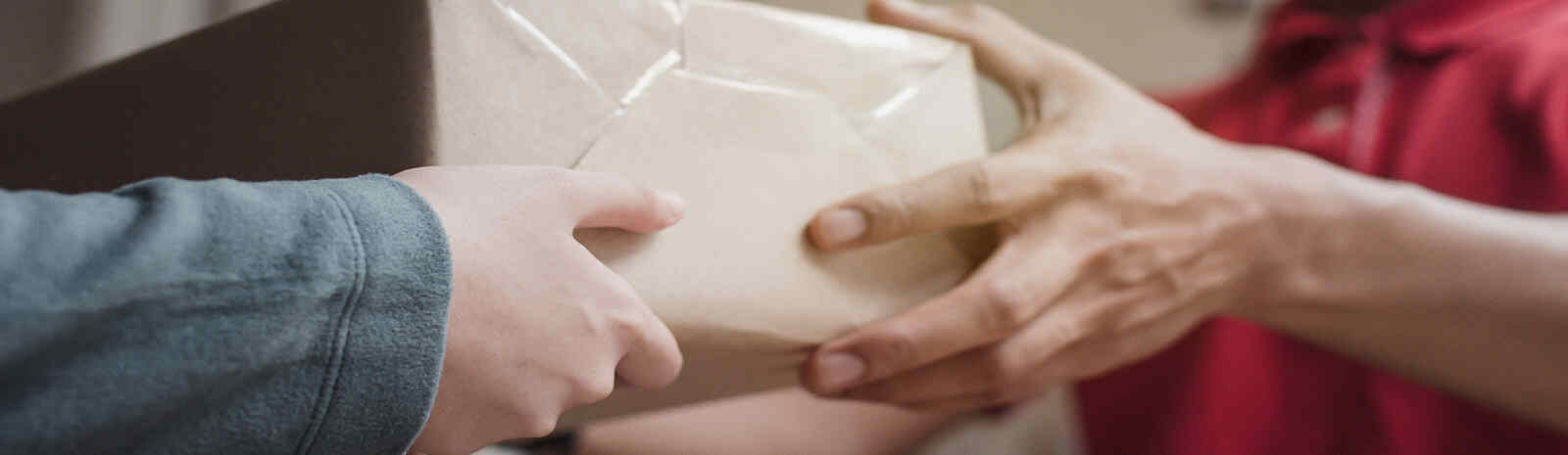 Zoomed in photo of hands giving a brown square package to another set of hands