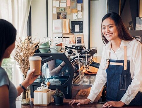 coffee shop worker smiling at customer holding coffee cup